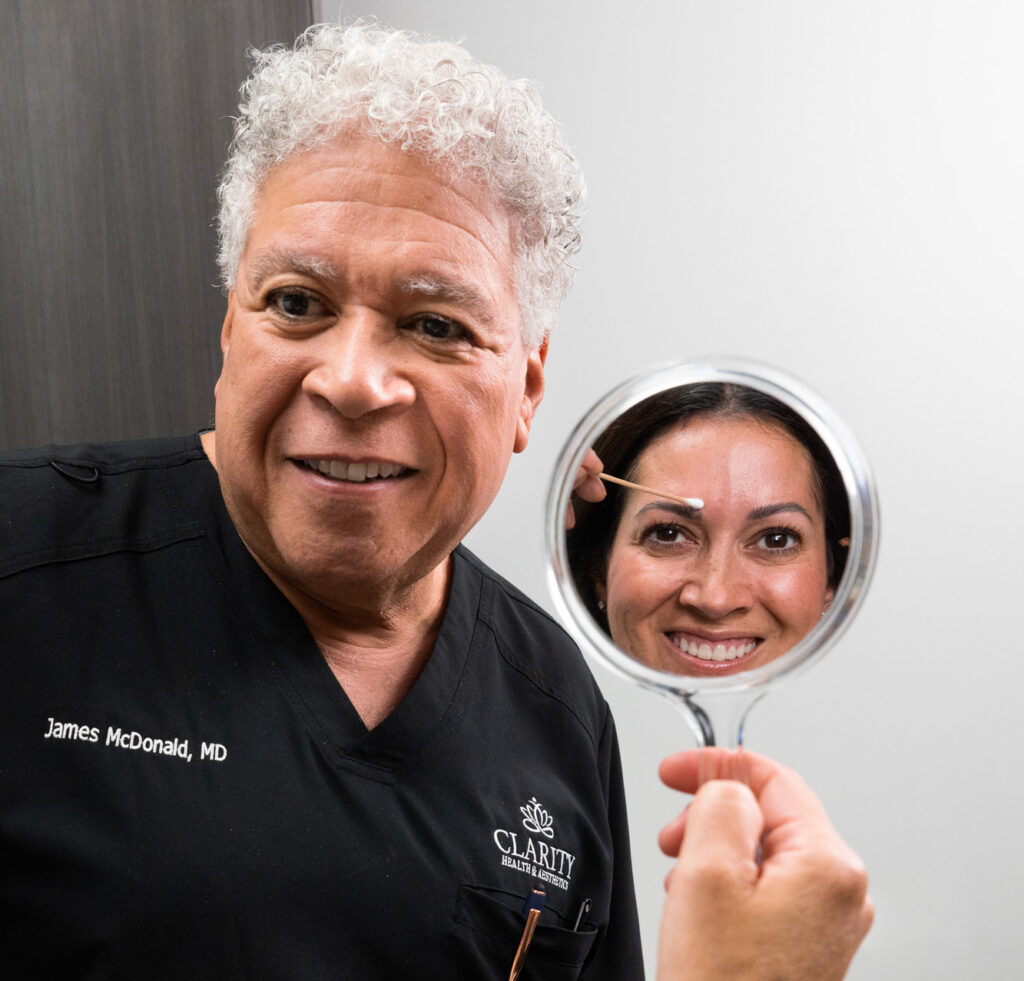 A woman looks in the mirror and smiles at the results of facial balancing in Kansas City