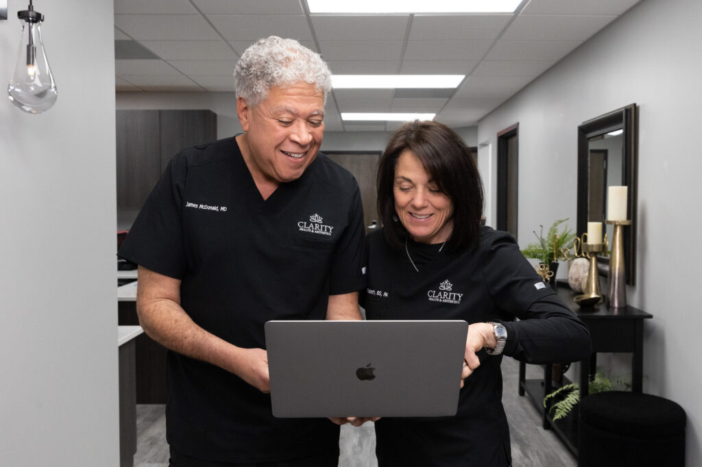 Providers from Clarity Health & Aesthetics looking happily at the before and after pictures of patients and celebrating the transformation their patients achieved after receiving lip fillers near Kansas City.