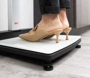 A patient stands on a scale after wonder, wondering, 'how can I lose stomach fat in Kansas City?'