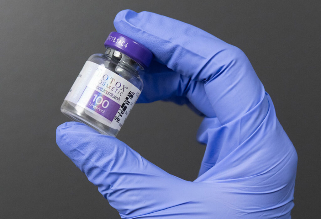 A provider from Clarity Health & Aesthetics holding up a 100 unit vial of Botox, showing how they prioritize safe treatments as a trusted aesthetic clinic in Kansas City.